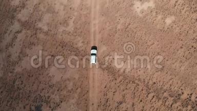 从4x4路的空中飞过，汽车沿着砾石小径行驶。 在沙漠帕米尔高速公路上的白色越野车上方
